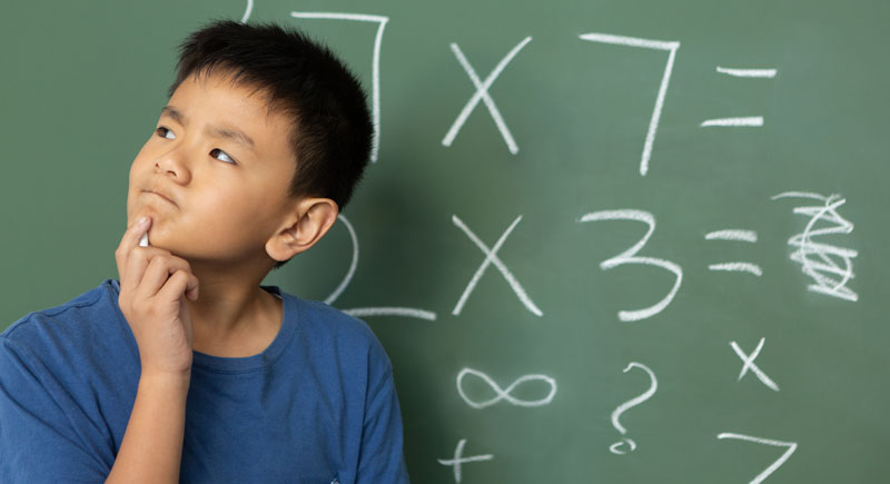 schoolboy-doing-math-on-green-chalkboard-in-a-class