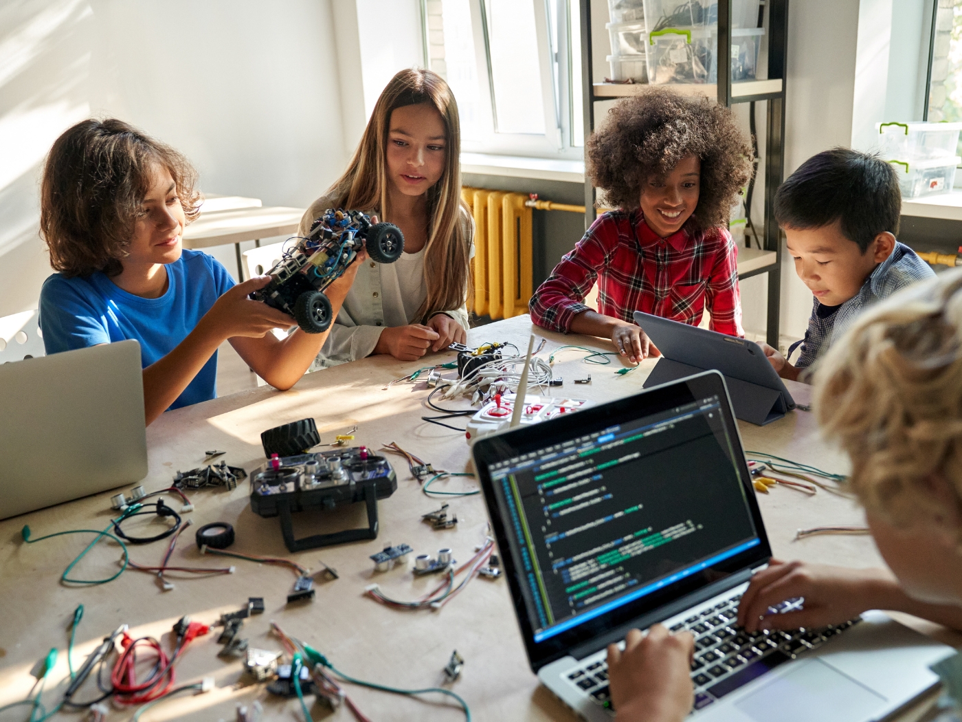 Students using laptops, coding tools, robotics, and AI learning resources in a premium classroom